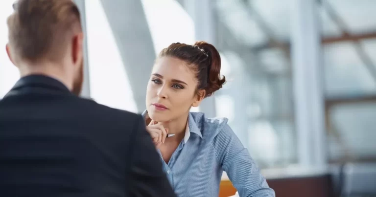 Woman in blue shirt talking to man in a suit, getting information for insured parties as part of a legal claim