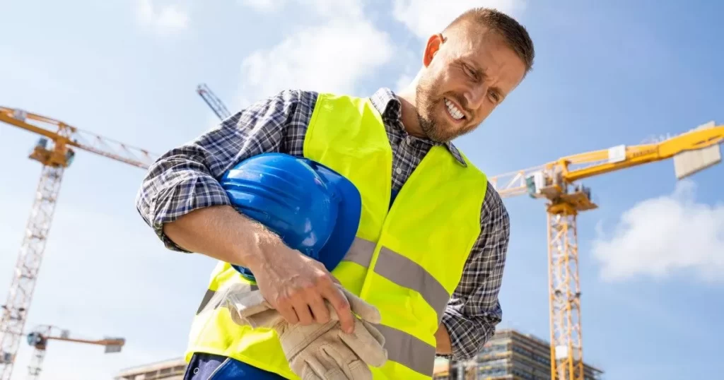 Construction worker with yellow vest and carrying a blue hard hat, during a workers compensation investigation