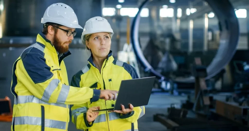 Man and woman in high visibility vests and hard hats conducting an ICAM Investigation