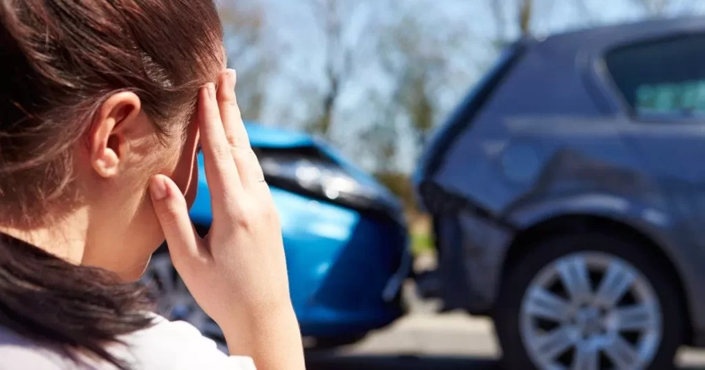 Woman holding hand to her head as she observes car accident in background. Image represents CTP investigations